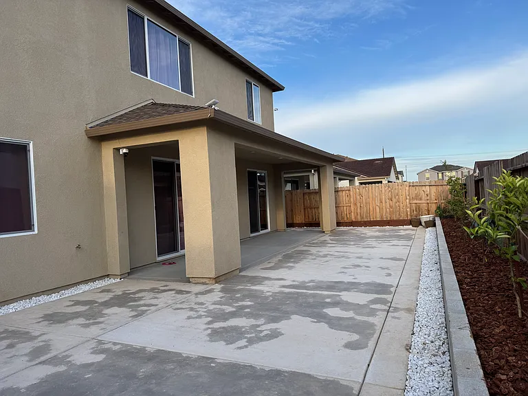 View of backyard patio, fully landscaped with flower bed, drip irrigation, and fruit trees.