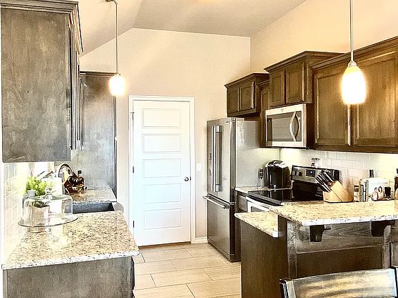 Kitchen has granite counter tops, stainless steel appliances, and pantry space.
