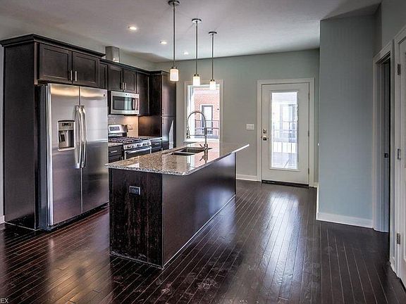 Modern kitchen with stainless steel appliances, granite island and counters. Pantry pictured on far right side
