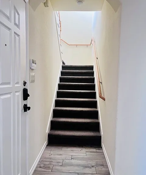 Entryway with keyless front door access and carpeted staircase leading to the second floor