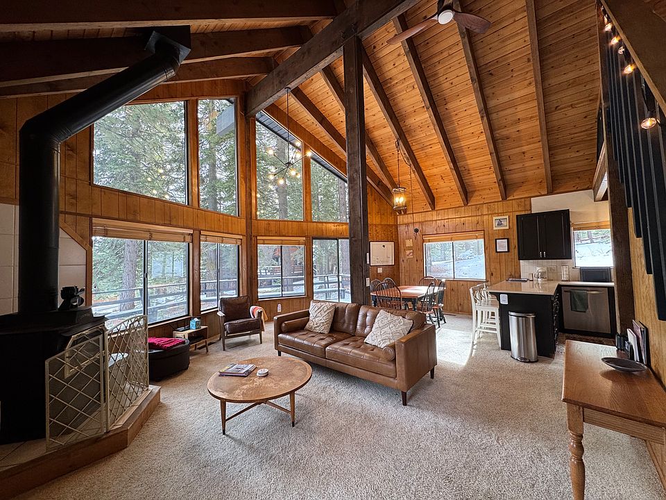 Expansive wall-to-ceiling windows with views of surrounding pines. Ceiling fan to stay cool in summer months, wood-burning stove to stay warm in winter months.