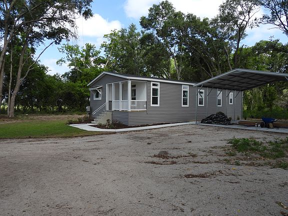 Side view of the house including the crushed concrete driveway and covered carport.