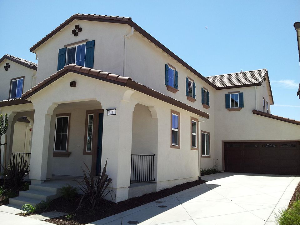 Front of the house with garage and 3 car driveways. Tile roof. Solar panels