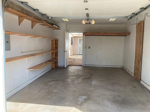 Built in shelving in 1-car garage with 1 automatic door opener. Walkway leads to back door of ohana.