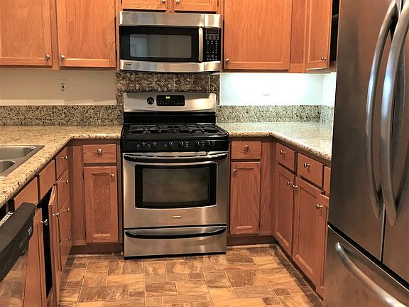 Granite kitchen counter top with gas stove, refrigerator, and dishwasher.