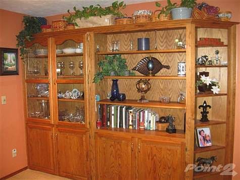 Built in book case and china cabinet in dining area with recessed lighting above and corner display shelves on the side.