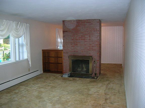 Fireplaced living room with picture window, wood floors under carpet