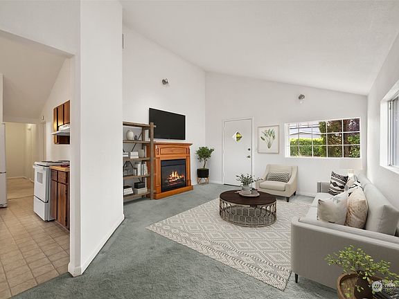 Spacious LR w/vaulted ceiling(Virtually Staged). Actual electric fireplace is movable & stays w/home.>