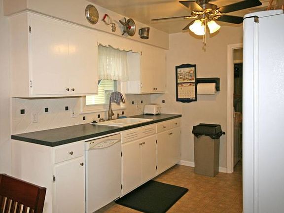 Opposite view of the kitchen features new sink and counter tops, faucet and cabinet hardware. Cabinetry has all been professionally painted and looks just like new with new hinges and hardware.