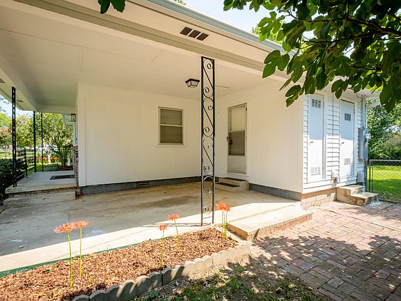 Covered Carport with attic access, door to outside storage area and brick side patio