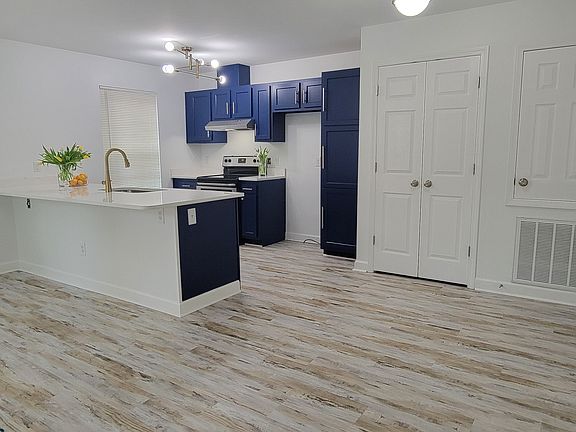Newly renovated townhome, open floor plan. The kitchen features navy blue cabinets accented with gold hardware, white quartz counter tops, stainless steel appliances, kitchen sink/gold faucet, modern lighting, LVP flooring, white walls through out.