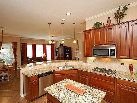 The kitchen is finely appointed with abundant cabinetry, granite counters, tile backsplash, built in