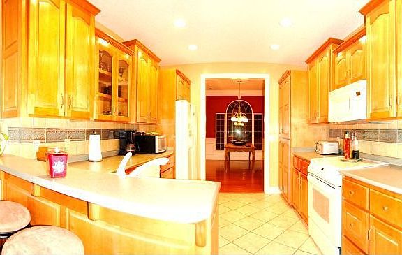 Large galley-style kitchen with ceramic tile, crown molding & bar