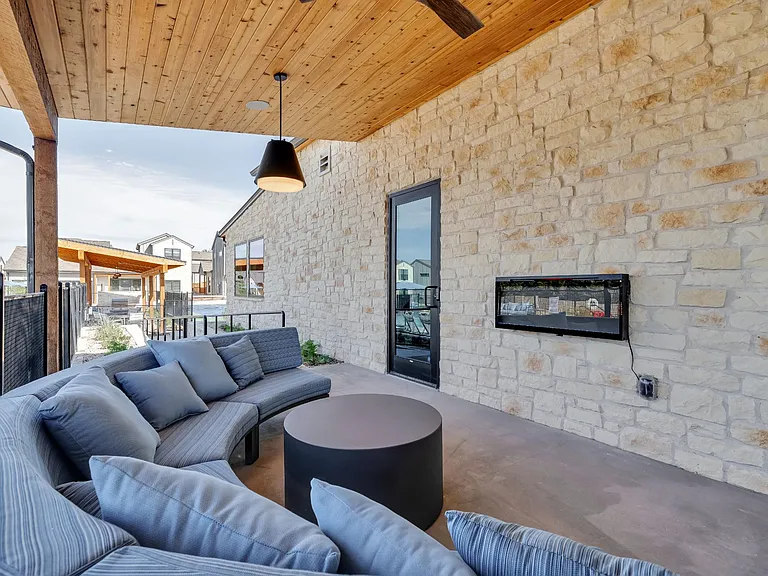 A modern living room with a curved sofa and a stone wall.