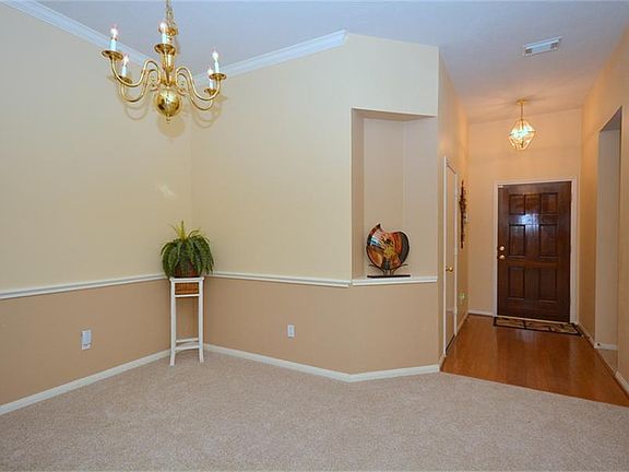 Wood floor at entry opening into an art niche and a large dining area in tasteful neutral colors.