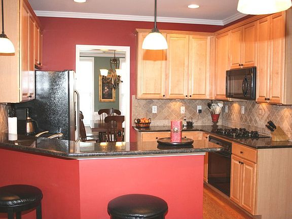 Granite kitchen w/ maple cabinetry, breakfast bar, black appliances, hardwoods