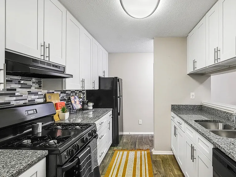 Kitchen with white cabinets, marble style countertops and hardwood style flooring. Kitchen with white cabinets, marble style countertops and hardwood style flooring.
