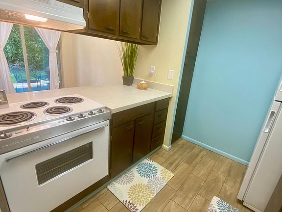 Brightly lit kitchen with fresh paint and restored midcentury cabinets opens to dining area with view to sliders and private patio.