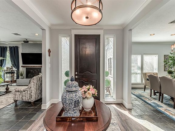 The formal foyer is flooded in light from the side lights flanking the solid wood front door. Wood look tile flooring, high ceilings with crown moulding, high end lighting and neutral wall paint accent this space.