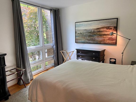 Serene bedroom looking at all of the trees in the back of the condo with floor to ceiling windows. Large closets and bureau.