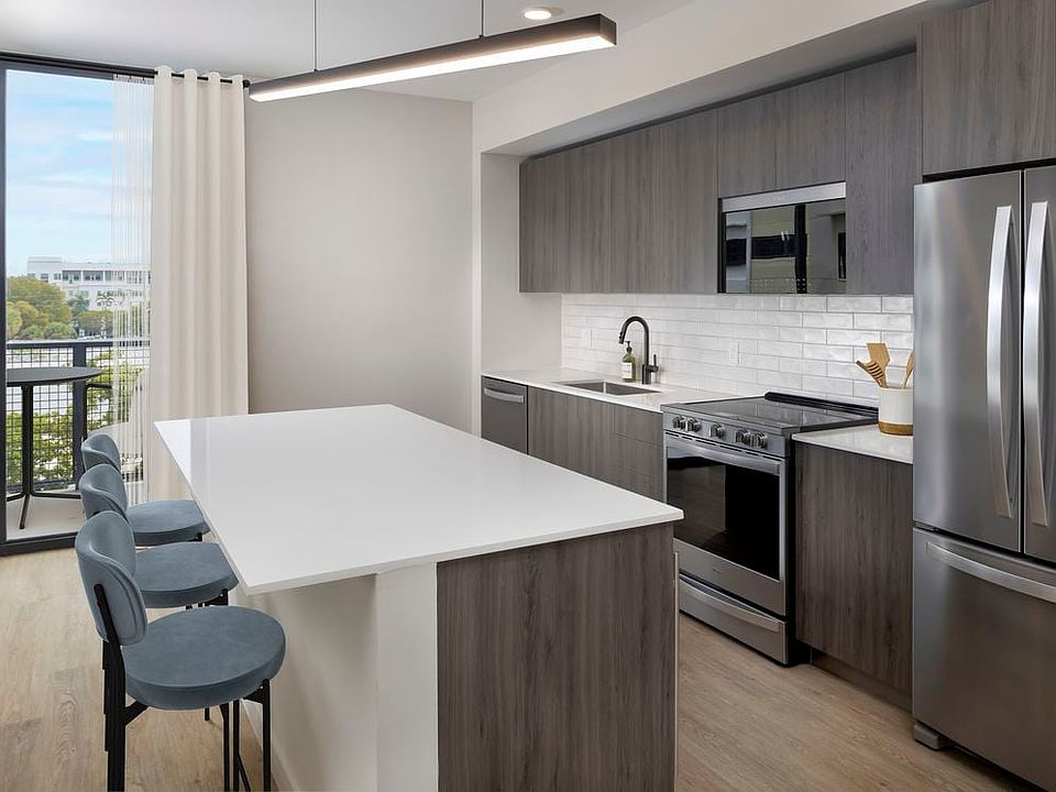 Upgrade Collection II Three-bedroom apartment kitchen with espresso cabinetry, white tile backsplash, white quartz countertop, and hard-surface vinyl plank flooring