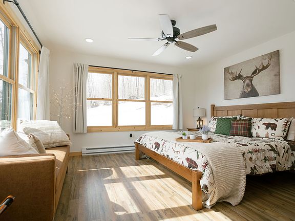 Primary bedroom with king bed, heated mattress, nightstands with nightlights and chargers, chest of drawers, and bench.