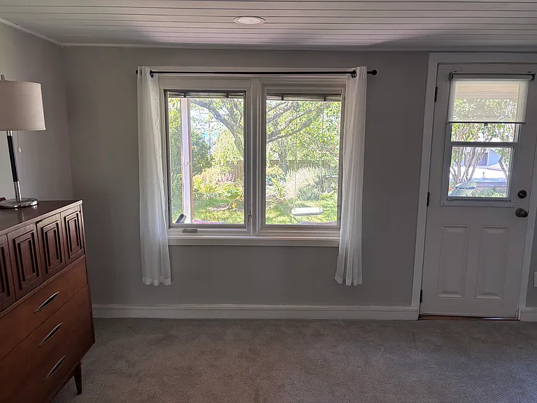 View out window from bedroom area of large second room, door to outside covered patio area under upstairs deck