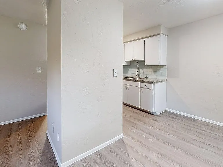 Modern apartment scene showcasing a sleek kitchen with bright cabinetry and elegant wood flooring.
