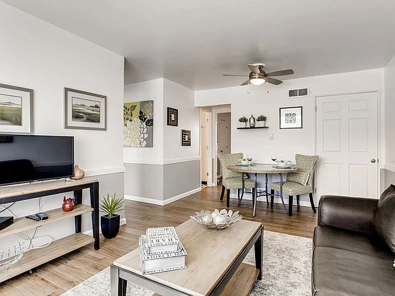 A living room with a black couch a television and a dining table