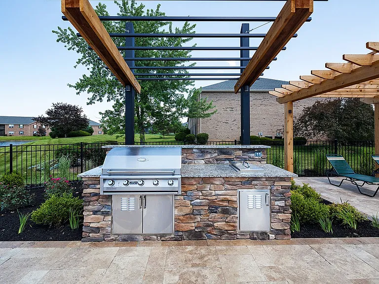 A built-in stone BBQ beneath a timeless wooden pergola creates the perfect outdoor space for dining and connection.