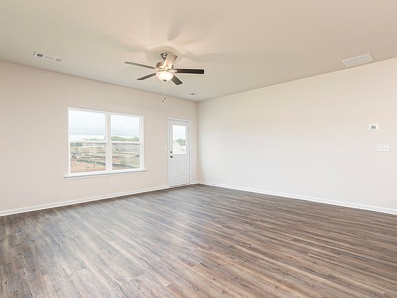 Bright and spacious family room with large windows and wood-style flooring.