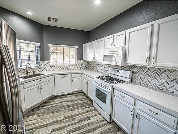 Modern white kitchen with mosaic backsplash and windows looking outside