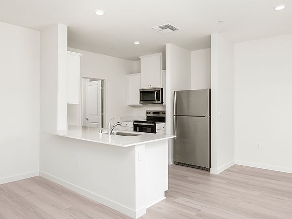 The kitchen has stainless steel appliances and plank flooring.