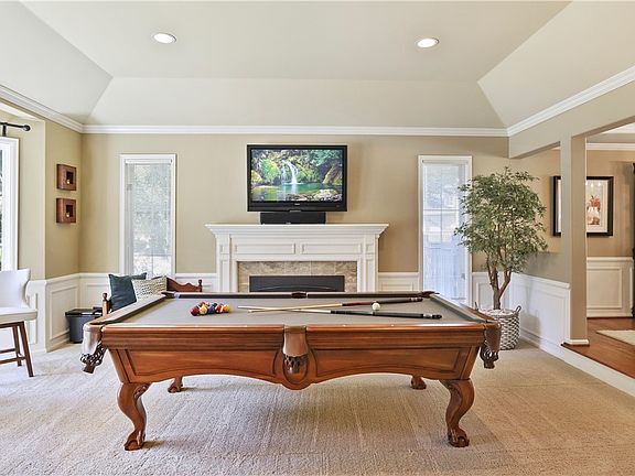 Formal living room offers gas fireplace with mantle and marble tile, coved ceiling, wainscoting, crown molding, and bay window bringing in an abundance of natural light.