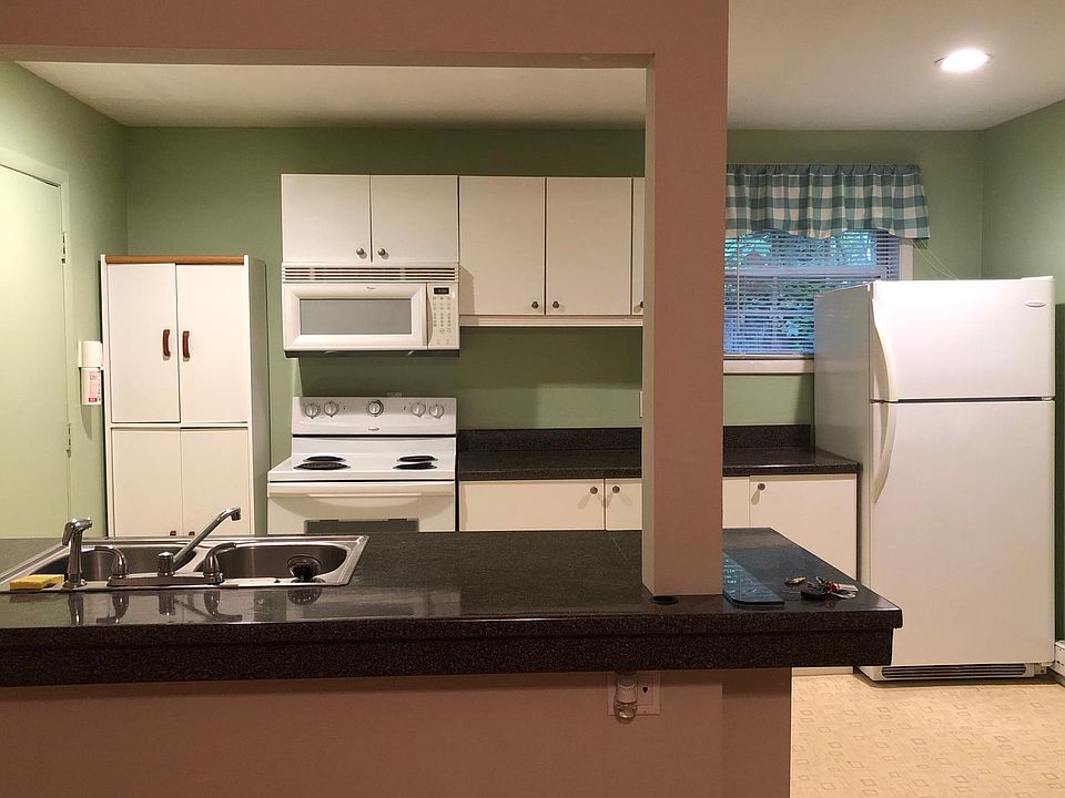 Bright white kitchen includes large fridge, stove, microwave & dishwasher.