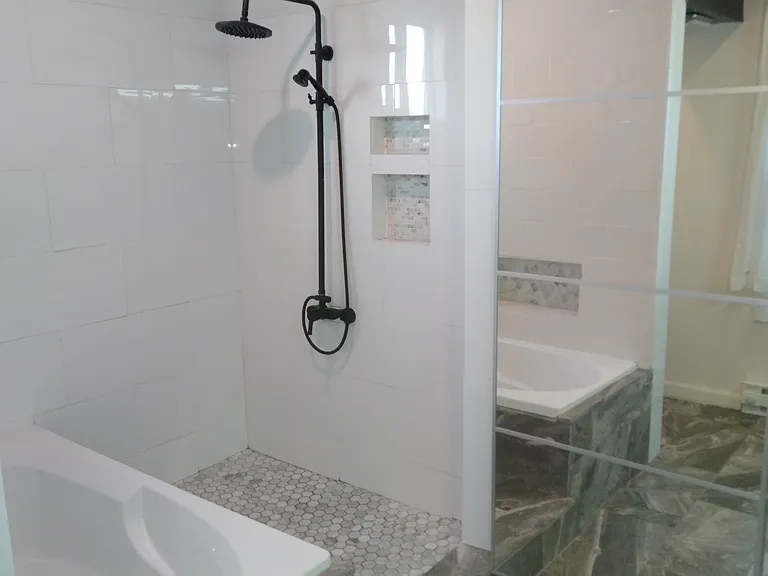 Upstairs bathroom with walk in shower. Sliding full length mirrors conceal shelving and hamper space.