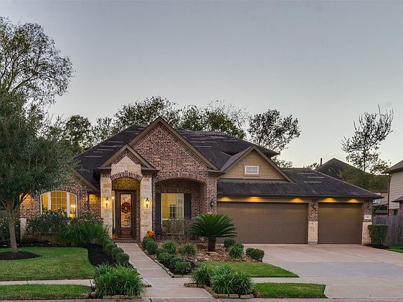Attractive Stone and Brick Elevation along with Exterior Lighting above Garage are a great backdrop for the Forest Like Setting and Mature Landscaping, both Front and Back, that this extraordinary home boasts.