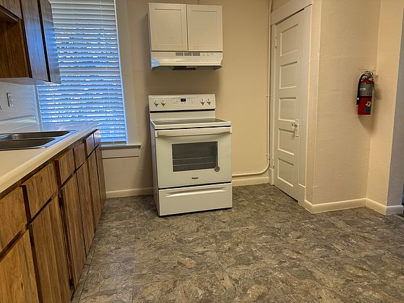 Newer glass-top range. Hood with light and fan. Cabinet above. New window blinds.