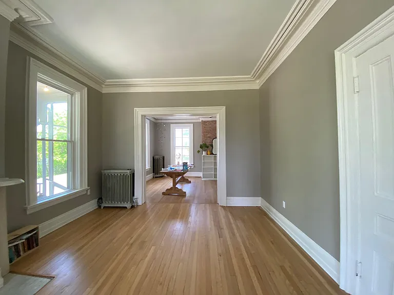 View from living room with front window at back looking into dining/kitchen.