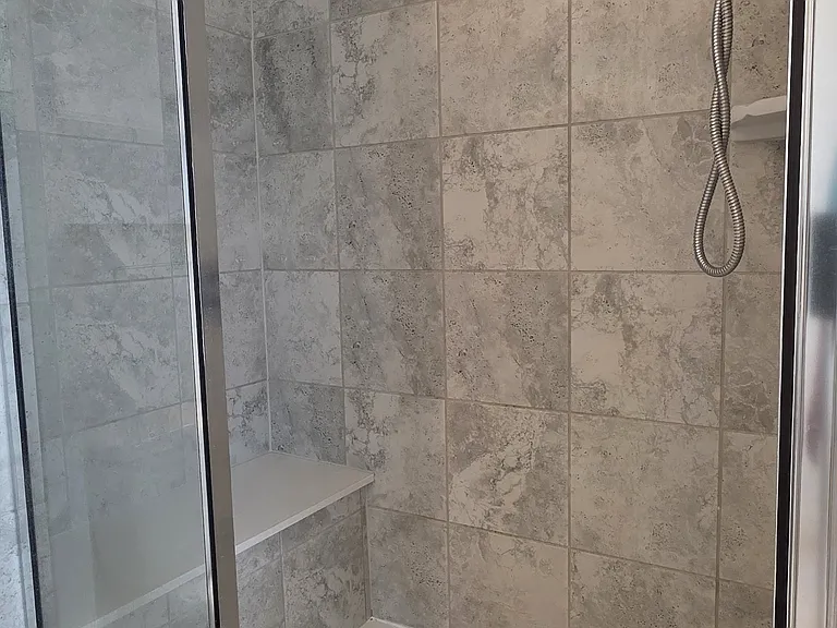 Walk-in shower with bench seat and tile backsplash