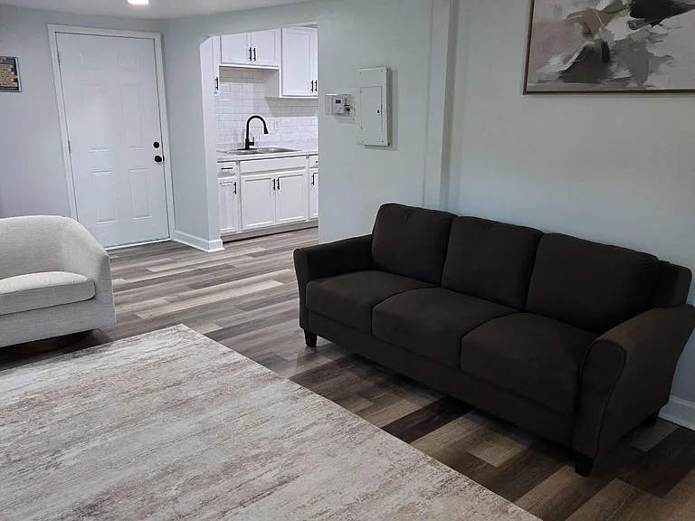 Open living area with durable flooring, comfortable seating, and convenient access to a compact kitchenette with ample cabine