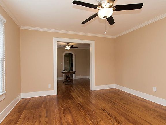 Another view of the living room with refinished hardwood floor and cased doorway leading to dining room