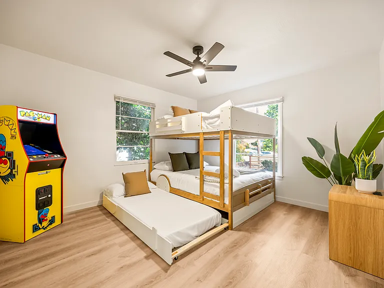 Fun and family-friendly bunk room featuring a queen-over-queen bunk bed, twin trundle, arcade game, and plenty of space for kids to unwind and enjoy.