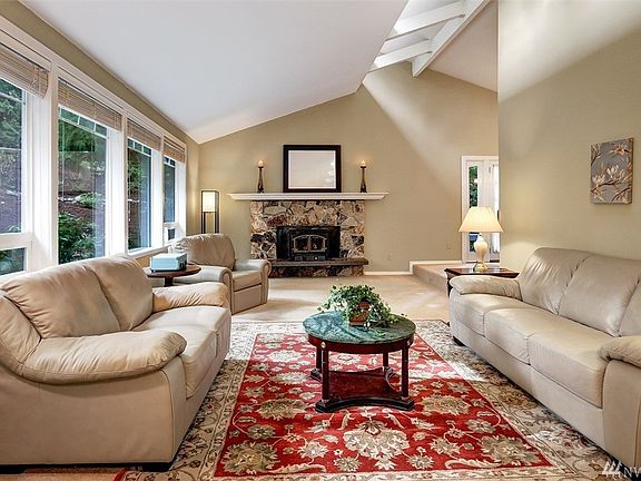 The large formal living room boasts a tall vaulted ceiling with celestial windows, stone wood burning fireplace and a wall of windows framing the charming, private front yard. 