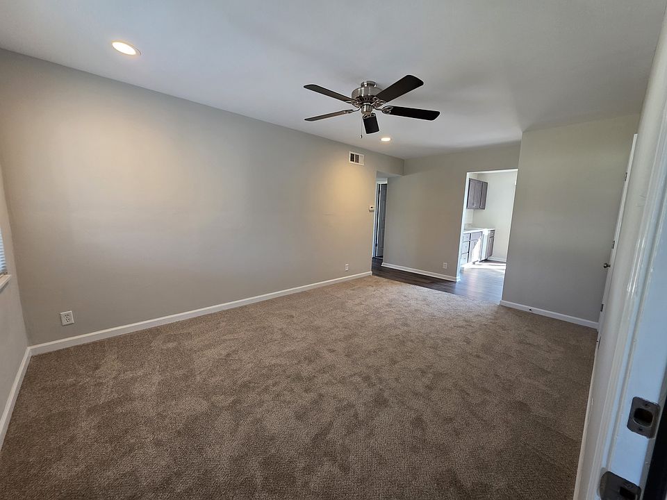 Living room with new ceiling fan, can lights, new carpet and fresh paint.