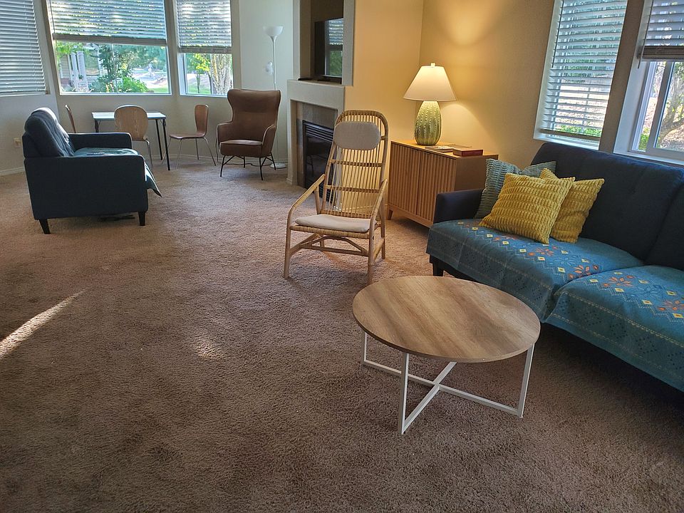 long living area with two seating areas, one in front of the fireplace, showing abundant natural light