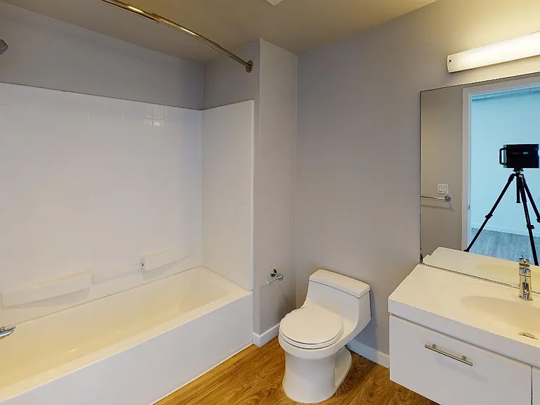 Apartment bathroom with wood-style flooring.