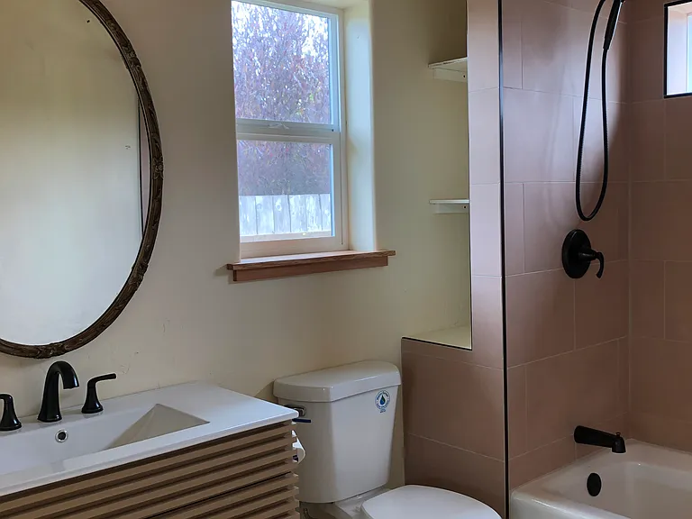 The bathroom. The bathroom has tile in the bath/shower, and on the floor. It also has a heated towel rack. There is a washer and dryer next to the bathroom.