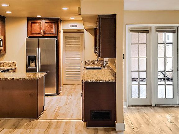 Beautiful kitchen with granite countertops, pho-wood flooring, and stainless steel appliances. French doors lead to a private patio.
