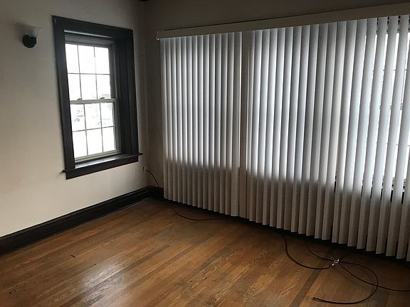 Living room includes hardwood flooring and 2 scounces on wall and new vertical blinds